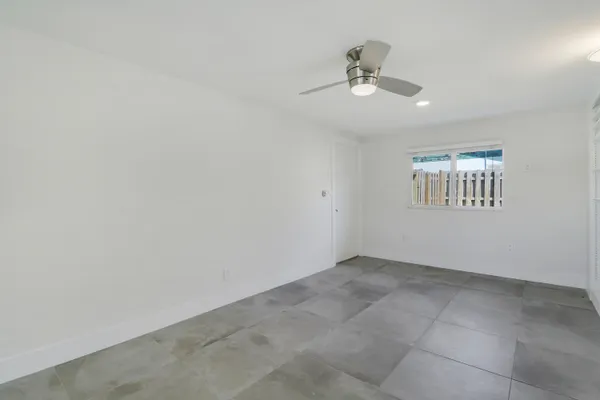 an empty room with windows and ceiling fan