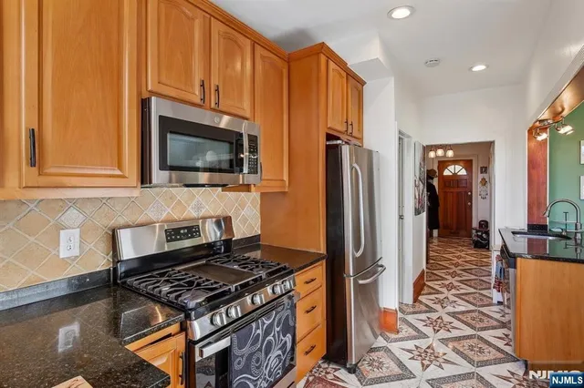 a kitchen with stainless steel appliances granite countertop a stove refrigerator and a microwave