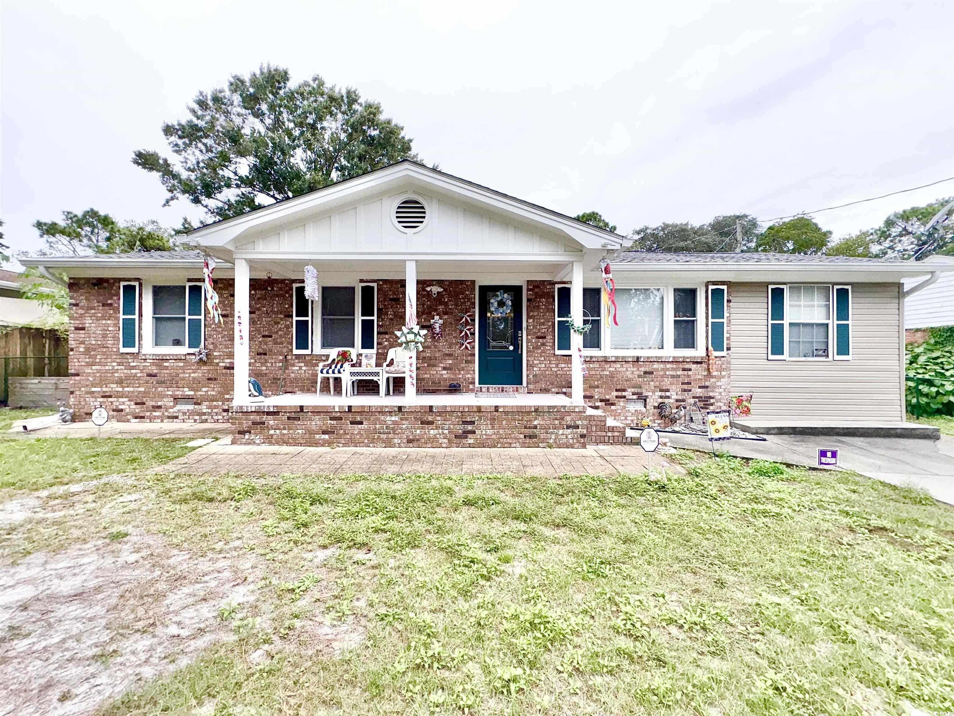 Single story home featuring covered porch, a front lawn, and brick siding