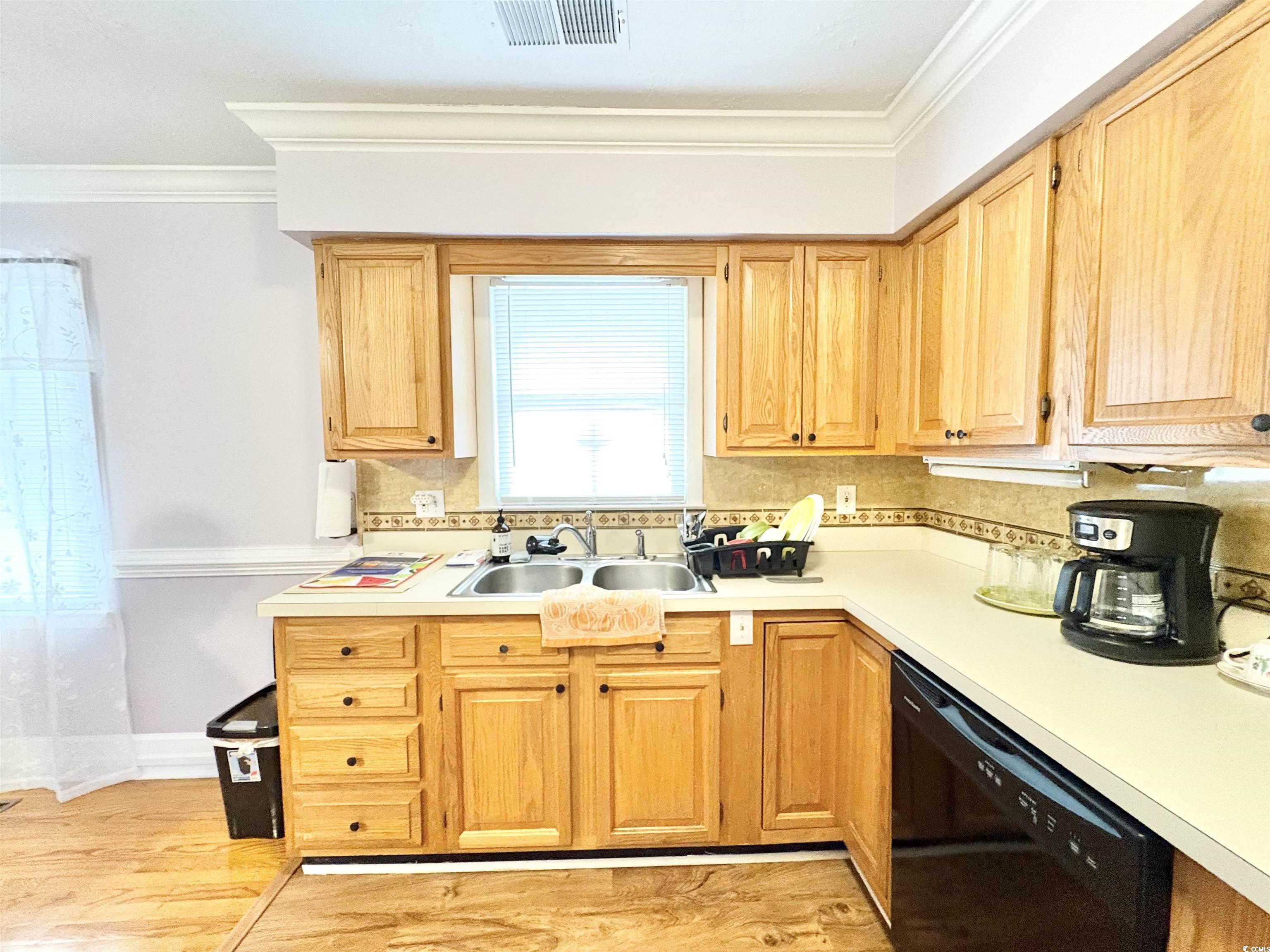 703 62nd Avenue North Myrtle Beach, SC 29577 - Photo 11 of 20 Kitchen featuring light countertops, dishwasher, light wood-type flooring, ornamental molding, and light brown cabinets