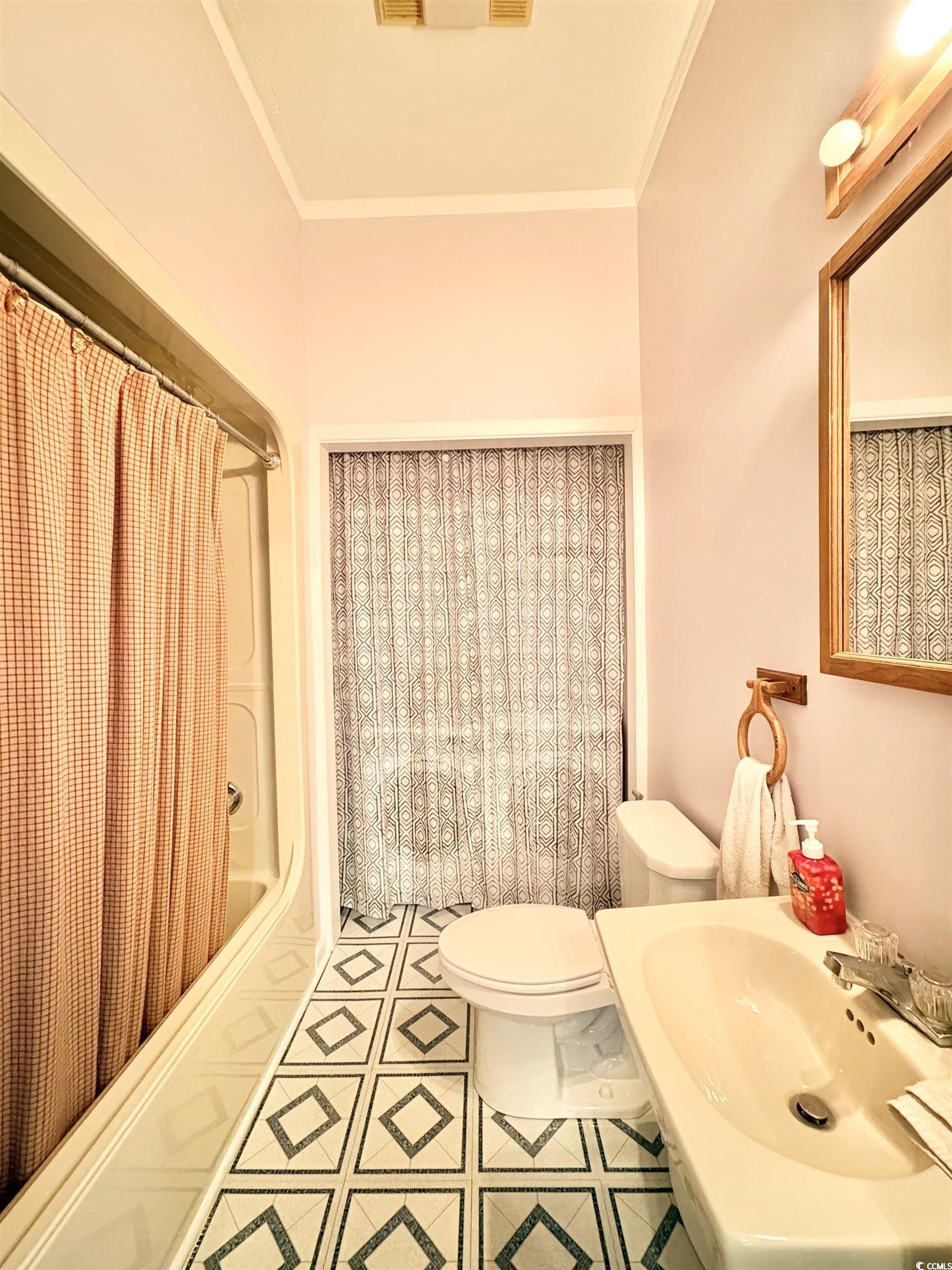 703 62nd Avenue North Myrtle Beach, SC 29577 - Photo 15 of 20 Full bathroom featuring shower / tub combo with curtain and crown molding