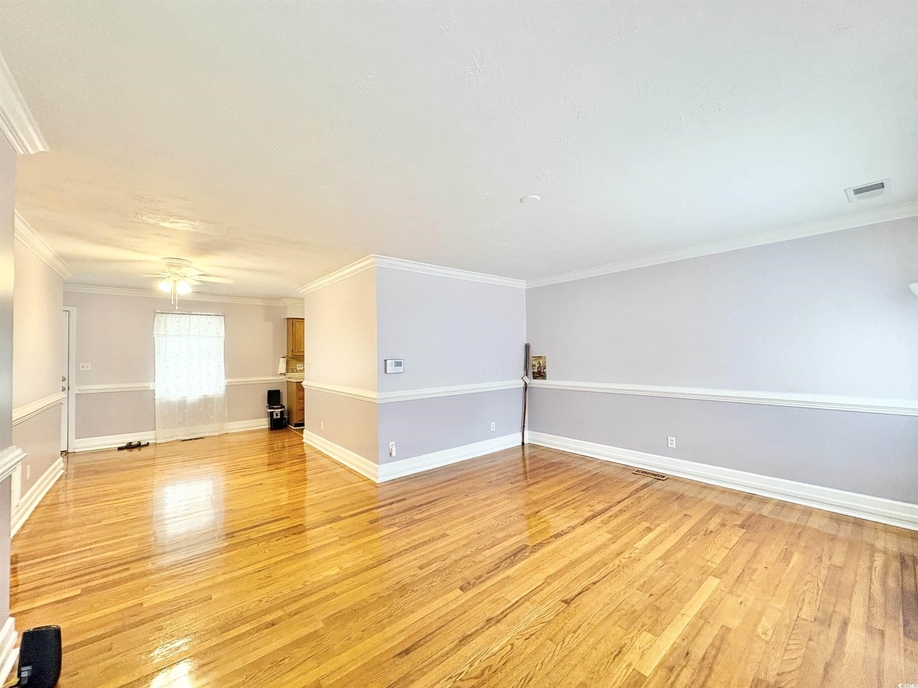 703 62nd Avenue North Myrtle Beach, SC 29577 - Photo 2 of 20 Empty room featuring light wood-type flooring, ornamental molding, and a ceiling fan