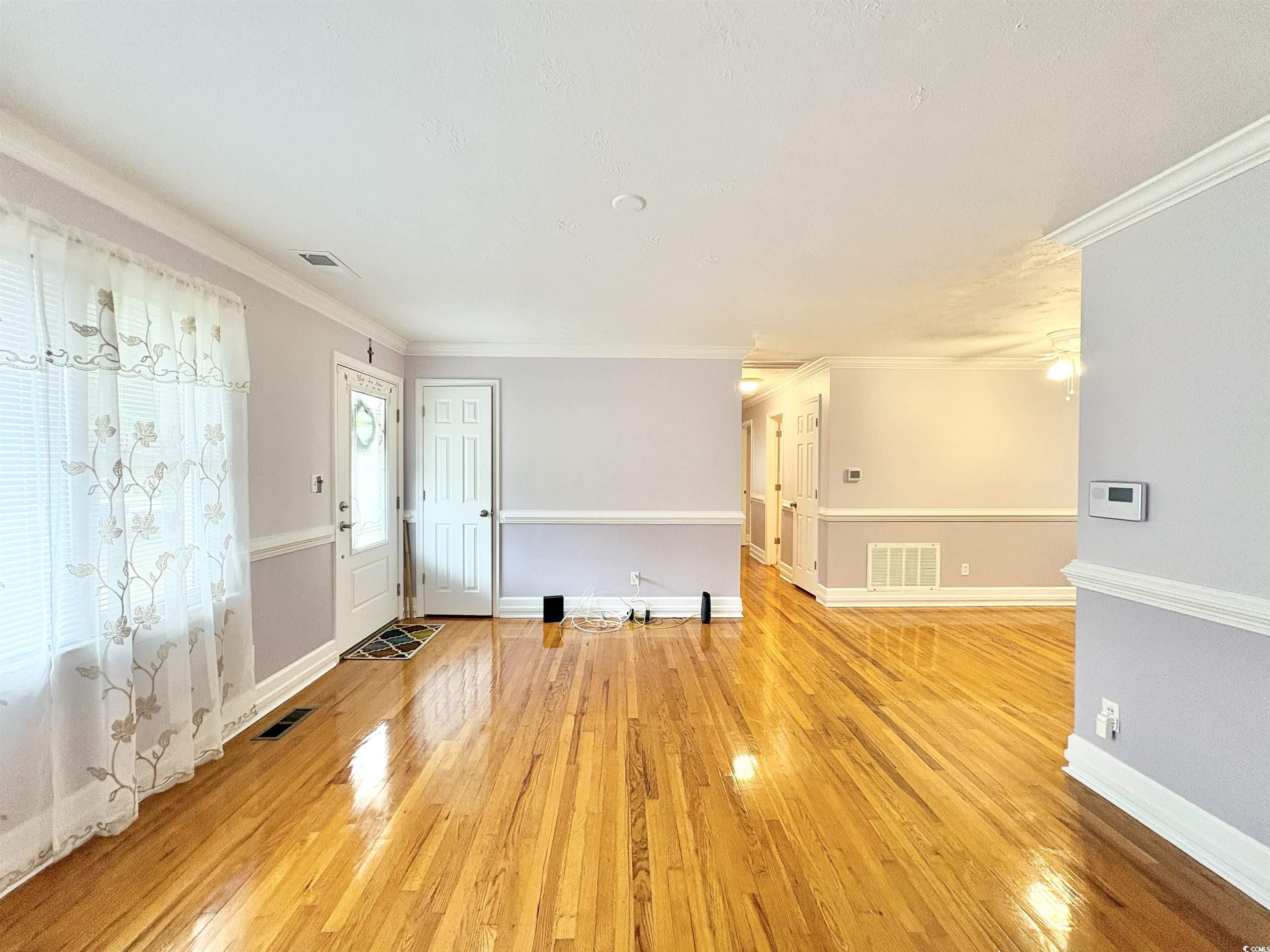 703 62nd Avenue North Myrtle Beach, SC 29577 - Photo 3 of 20 Unfurnished living room with ornamental molding and light wood finished floors