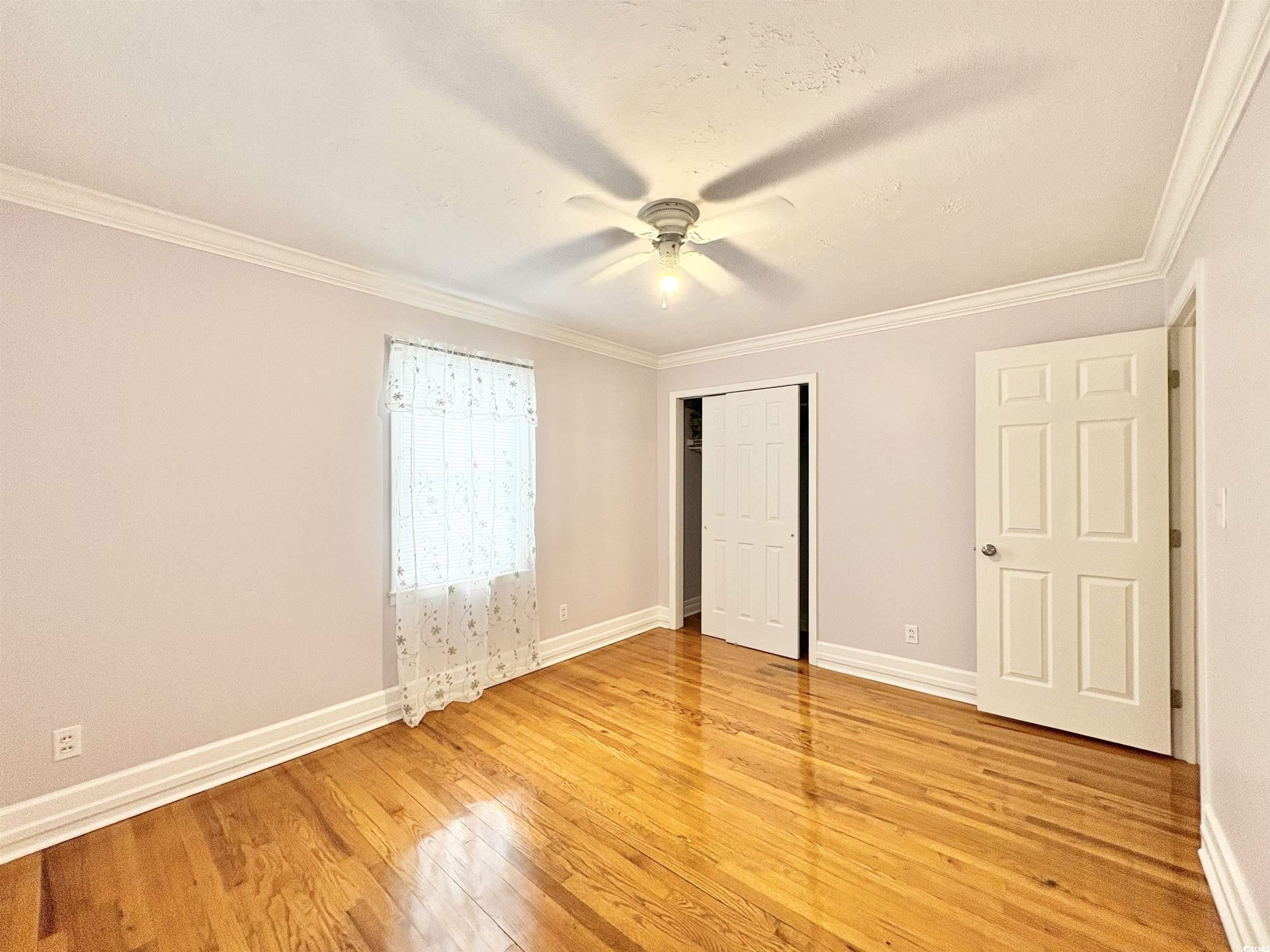 703 62nd Avenue North Myrtle Beach, SC 29577 - Photo 8 of 20 Unfurnished bedroom featuring crown molding, a ceiling fan, light wood-style flooring, and a closet