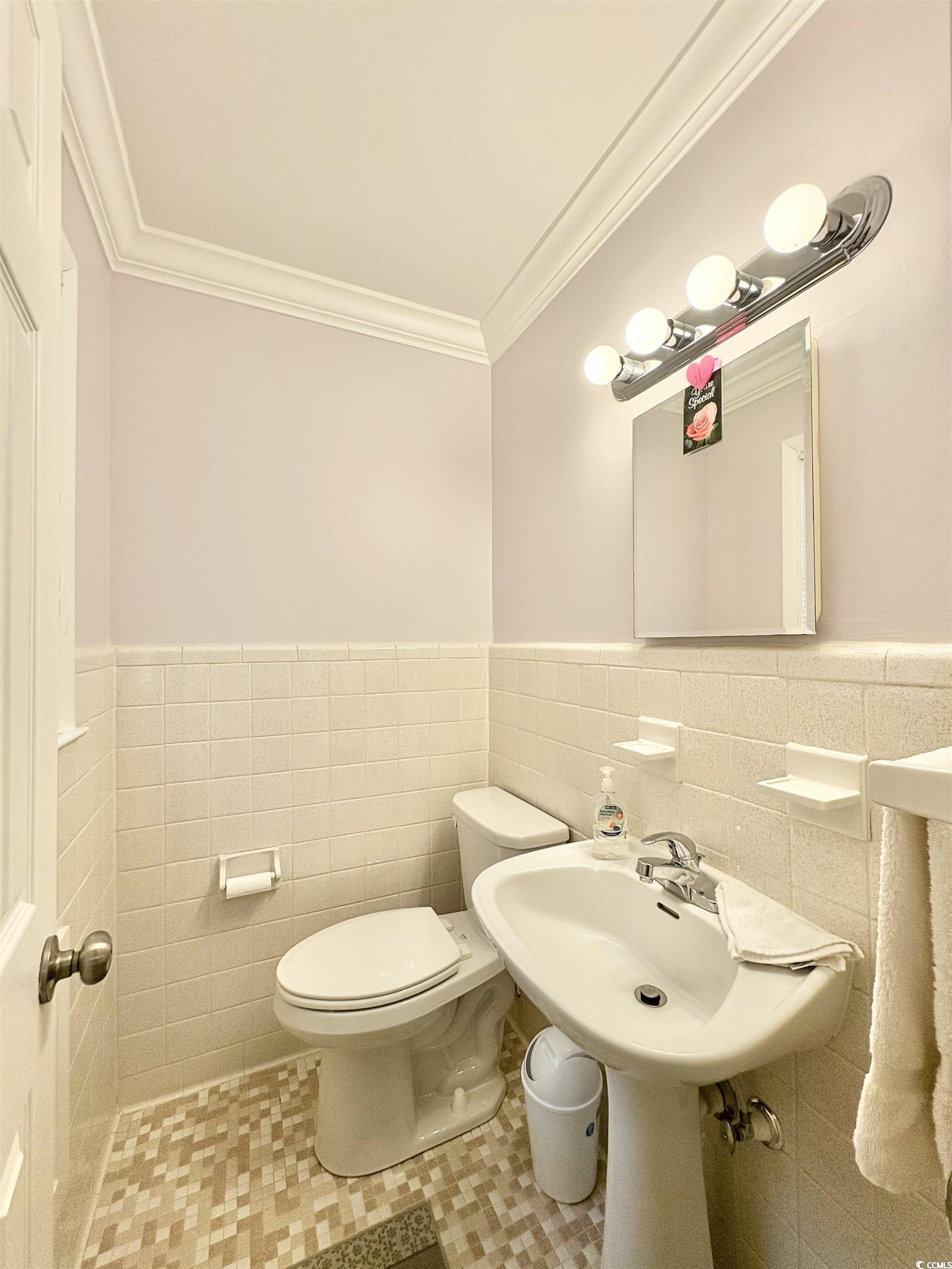 703 62nd Avenue North Myrtle Beach, SC 29577 - Photo 9 of 20 Half bathroom featuring wainscoting, tile walls, light tile patterned flooring, and crown molding