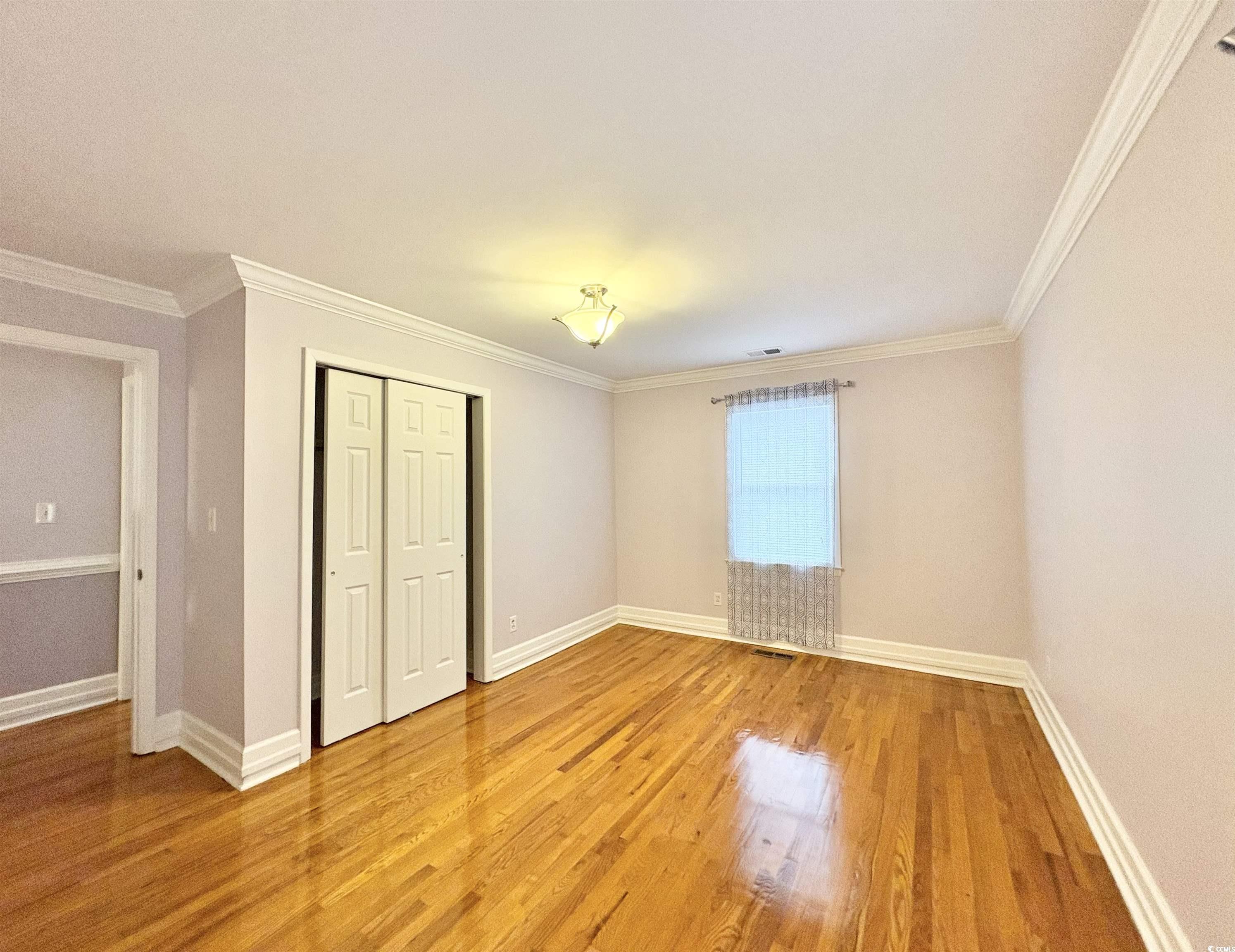 703 62nd Avenue North Myrtle Beach, SC 29577 - Photo 10 of 20 Unfurnished bedroom with ornamental molding, light wood-type flooring, and a closet