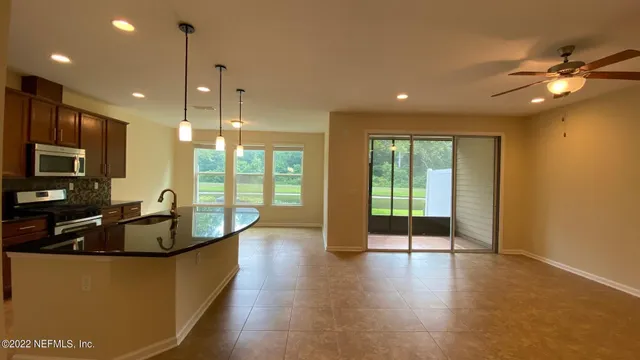 a dining hall with stainless steel appliances granite countertop a refrigerator a sink dishwasher a oven and a dining table with wooden floor