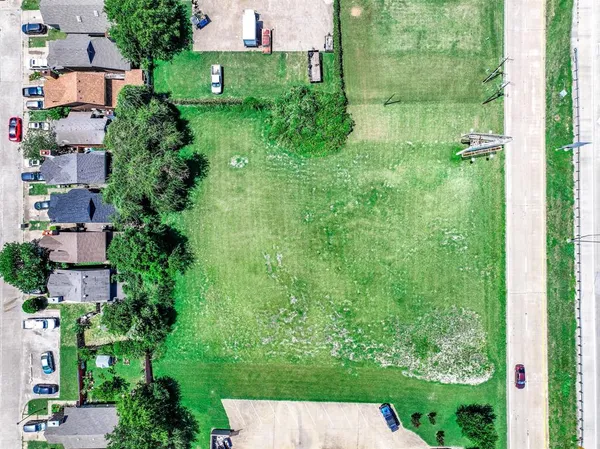 a view of a street with a big yard and a large tree