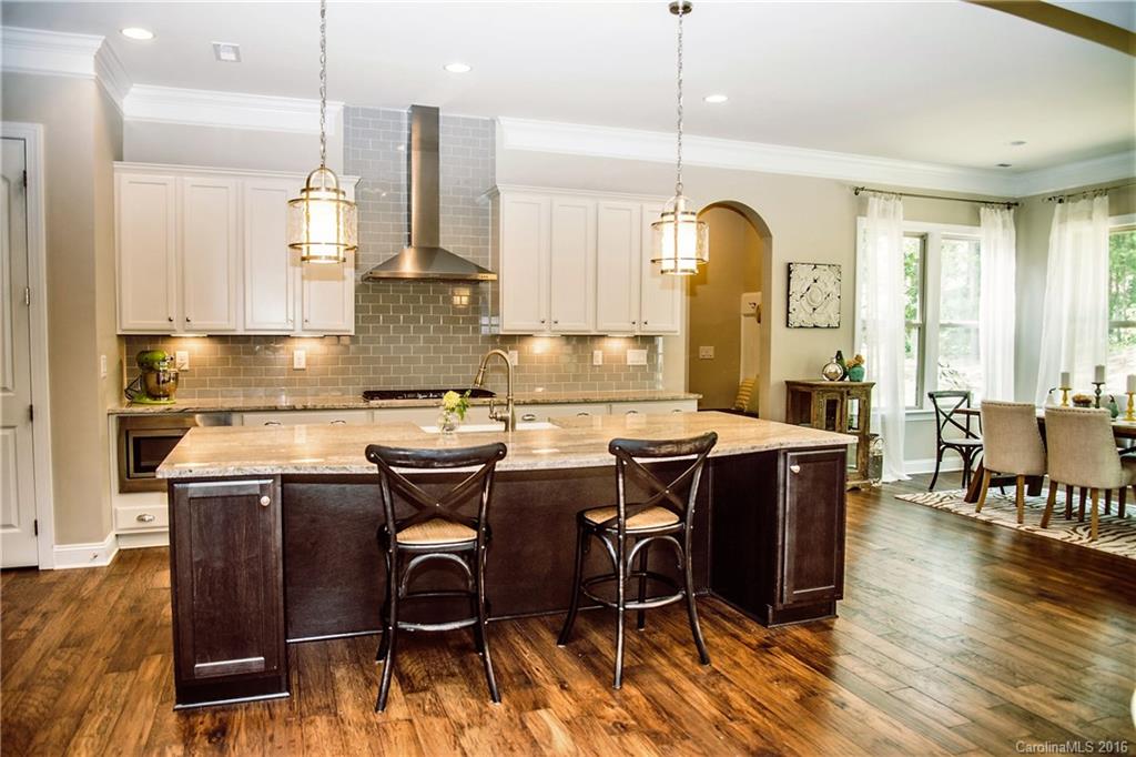 8086 Clems Branch Road Indian Land, SC 29707 - Photo 4 of 23 a open kitchen with stainless steel appliances granite countertop a stove top oven a sink dishwasher a dining table and chairs with wooden floor