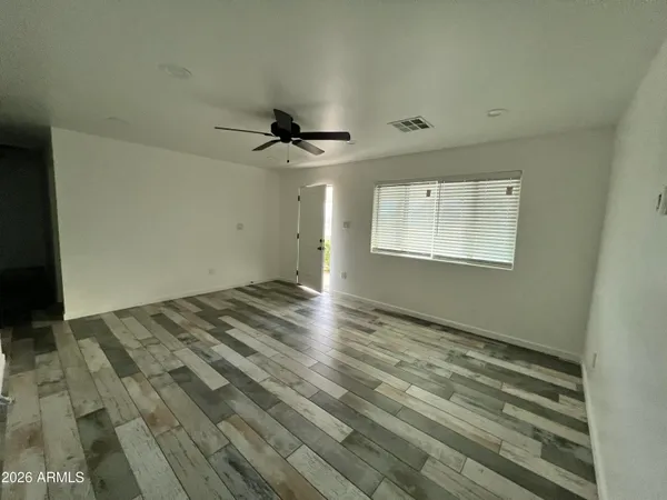 a view of empty room with wooden floor and fan