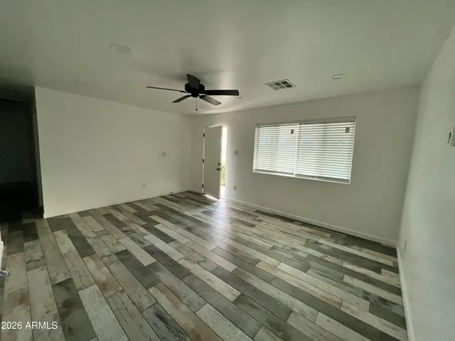 a view of empty room with wooden floor and fan