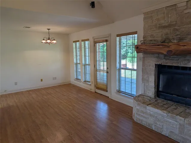 a view of an empty room with wooden floor fireplace and a window