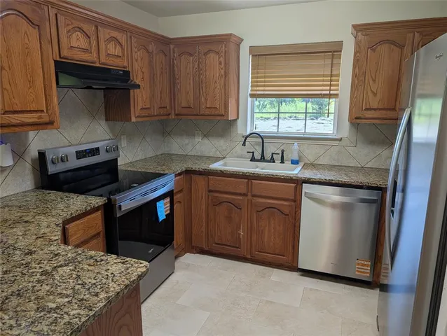 a kitchen with stainless steel appliances granite countertop a sink stove and microwave