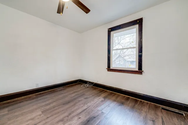 an empty room with ceiling fan and window