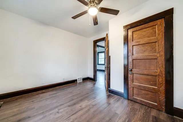 an empty room with wooden floor closet and windows