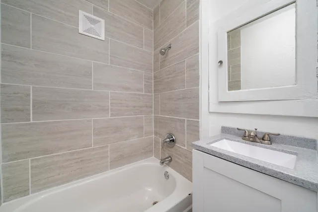 a white bath tub sitting next to a white sink and vanity