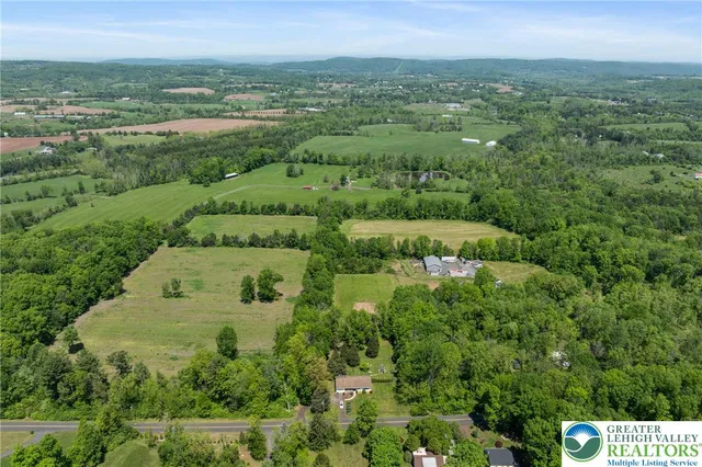 an aerial view of residential houses with outdoor space and trees