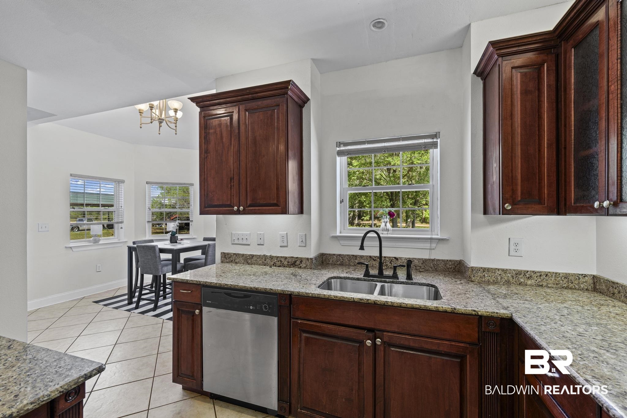 32875 Faircloth Road Lillian, AL 36549 - Photo 23 of 85 Kitchen featuring dishwasher, light stone counters, light tile patterned floors, a chandelier, and dark wood finish cabinets