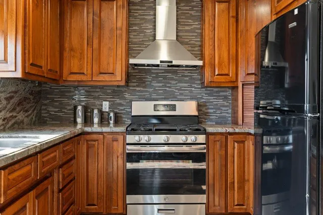 a kitchen with stainless steel appliances granite countertop wooden cabinets stove top oven and sink