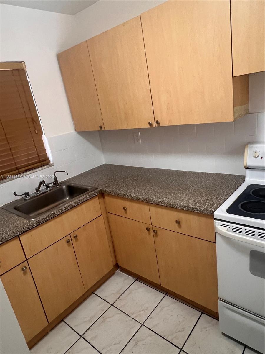 10851 Southwest 2nd Street, Unit K304 Sweetwater, FL 33174 - Photo 9 of 16 a kitchen with granite countertop white cabinets and white appliances