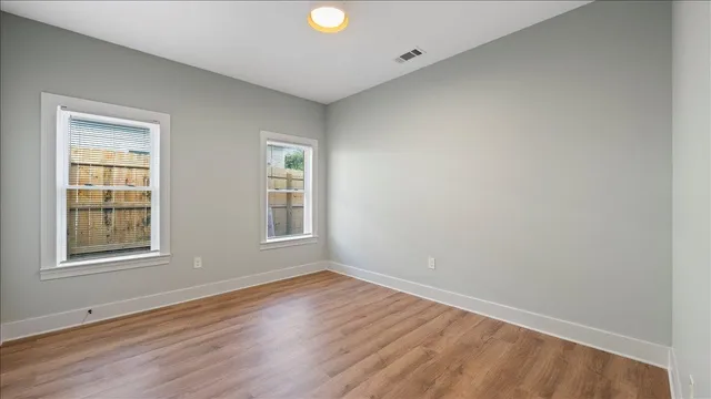 an empty room with wooden floor and windows