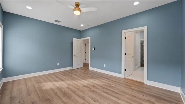 an empty room with wooden floor and a ceiling fan