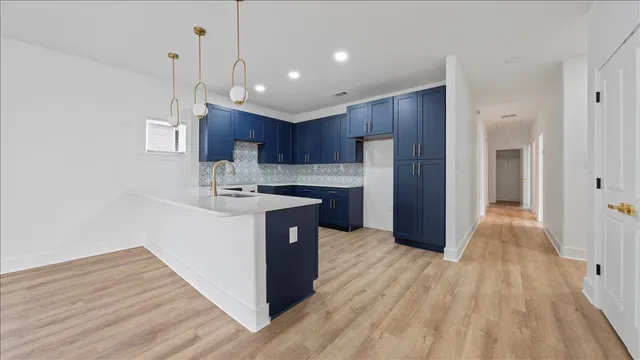 a kitchen with kitchen island wooden floors appliances and cabinets