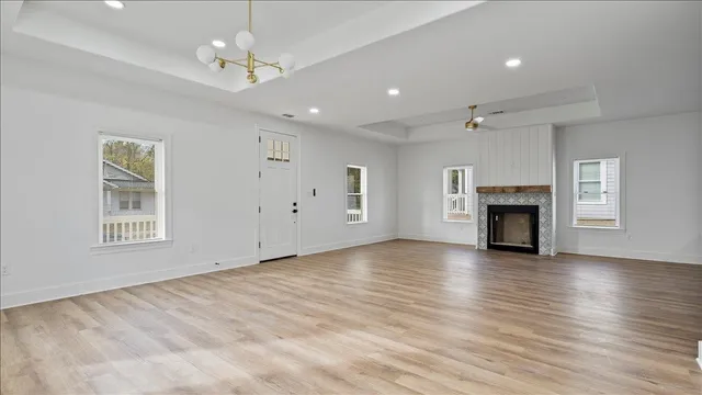 an empty room with wooden floor fireplace and windows
