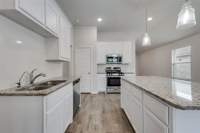 a kitchen with kitchen island granite countertop a sink stove and refrigerator