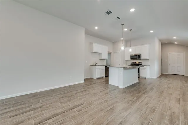 a view of kitchen with kitchen island wooden floors and stainless steel appliances