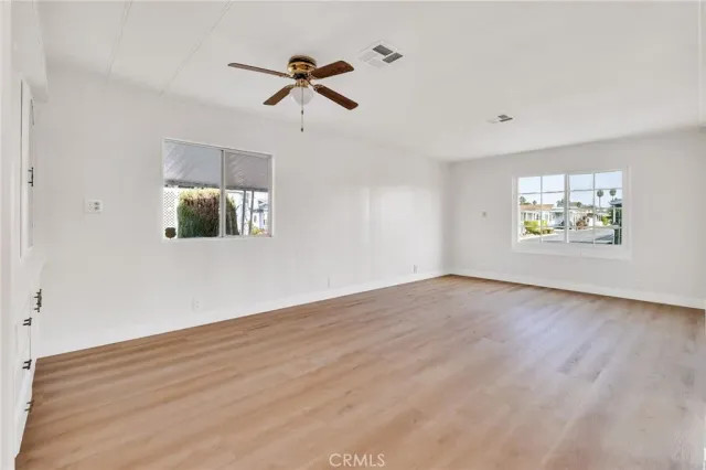 a view of an empty room with a window and wooden floor