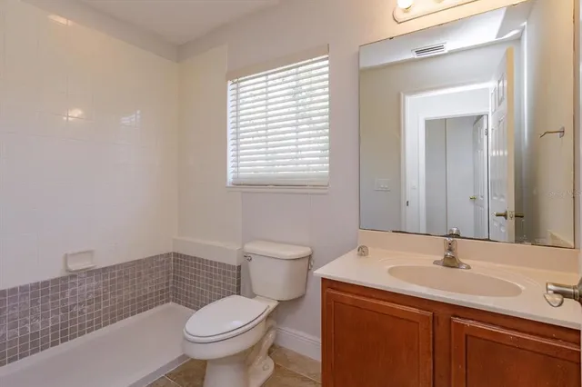 a bathroom with a granite countertop toilet a sink and a mirror