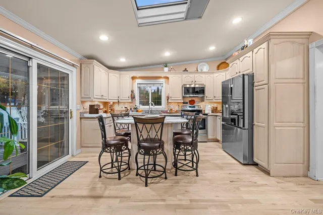a kitchen with stainless steel appliances kitchen island granite countertop a refrigerator a stove a sink a dining table and chairs with wooden floor