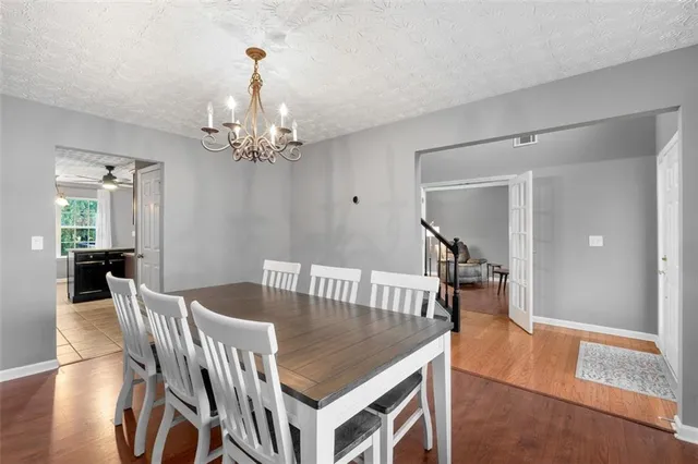 a dining room with wooden floor a chandelier a wooden table and chairs