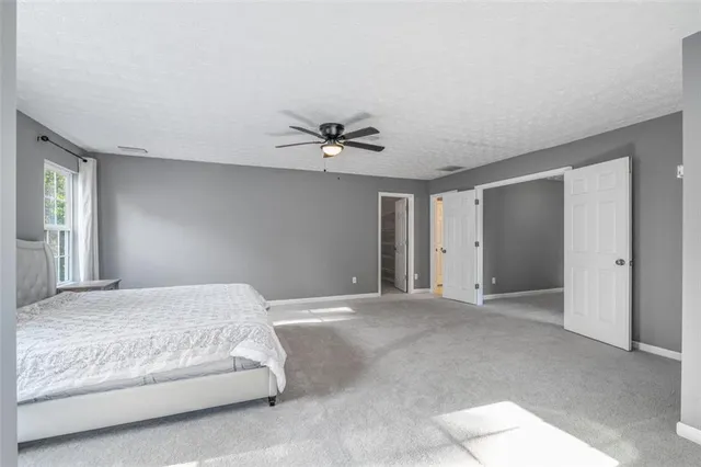 a spacious bedroom with a bed and a ceiling fan