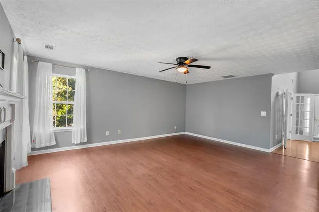 a view of an empty room with a window and wooden floor