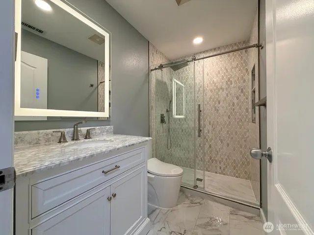 a bathroom with a granite countertop sink toilet and shower