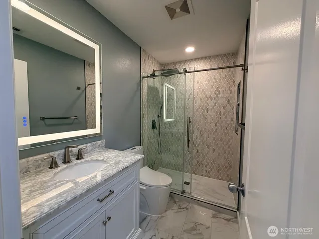 a bathroom with a granite countertop sink toilet and shower