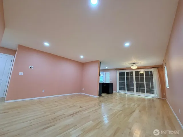 a view of empty room with a large window and refrigerator