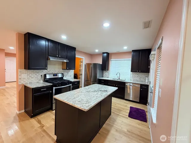 a kitchen with stainless steel appliances granite countertop a sink stove and refrigerator