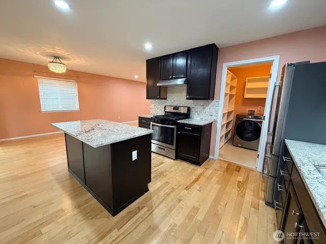 a kitchen with stainless steel appliances granite countertop wooden cabinets a stove top oven a sink and dishwasher