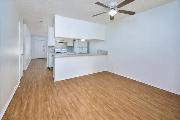 a view of kitchen and empty room with wooden floor