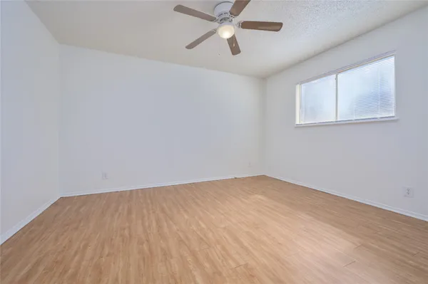 an empty room with a window and a ceiling fan