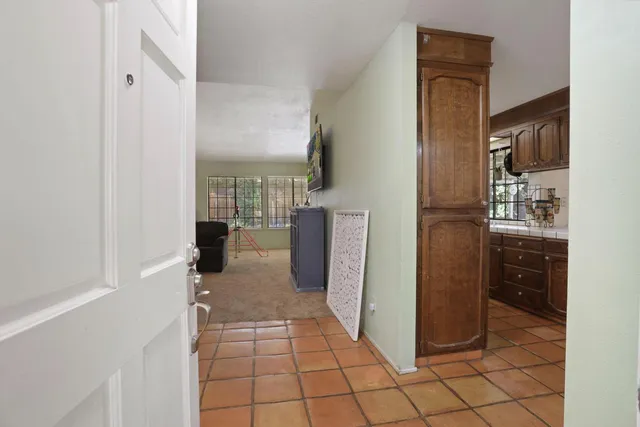 a view of a refrigerator in kitchen and an empty room