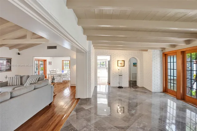 a living room with furniture a large window and wooden floor