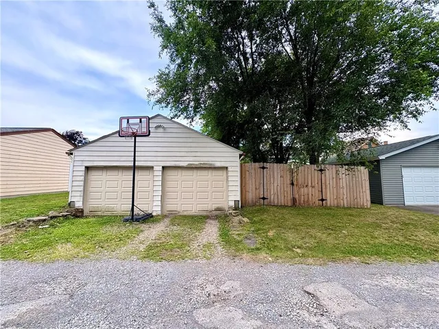a yellow house with a big yard plants and large trees
