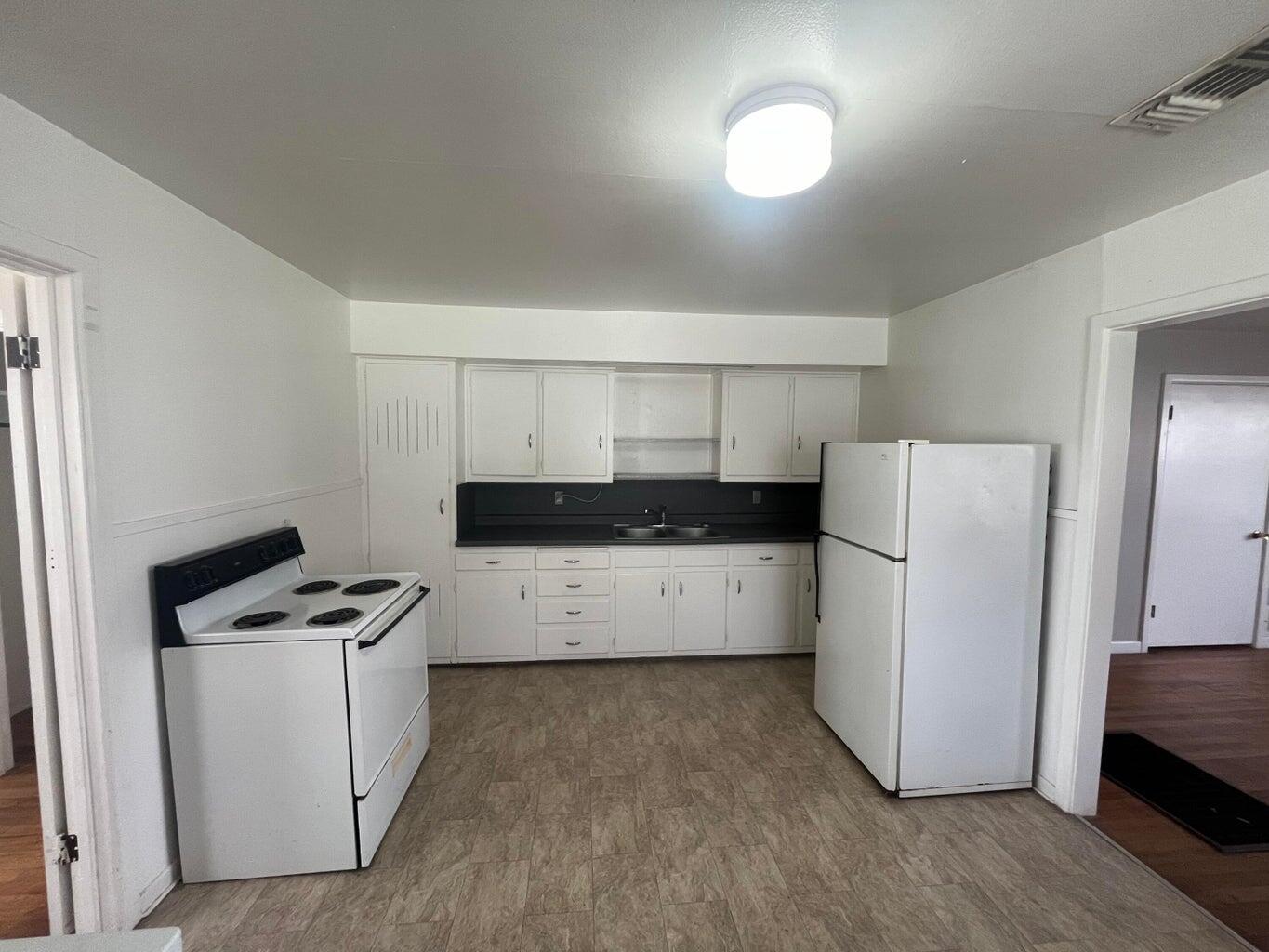 3113 33rd Street, Unit A Lubbock, TX 79410 - Photo 4 of 10 a kitchen with a refrigerator a stove top oven a sink and cabinets