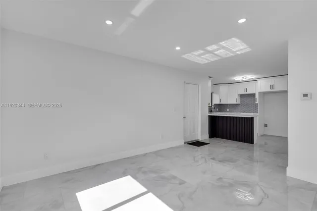 a large white kitchen with a refrigerator and a sink