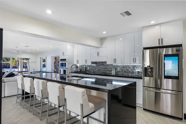 a kitchen with stainless steel appliances granite countertop a table chairs sink and cabinets
