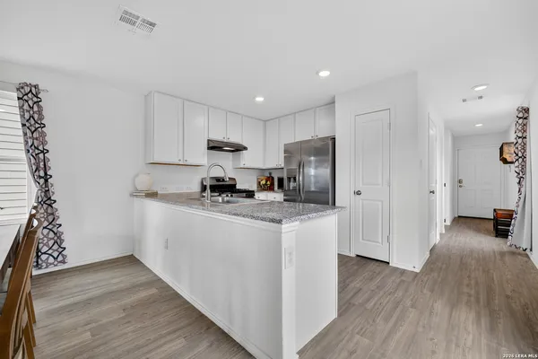 a kitchen with stainless steel appliances granite countertop a refrigerator a stove top oven a sink and dishwasher with wooden floor